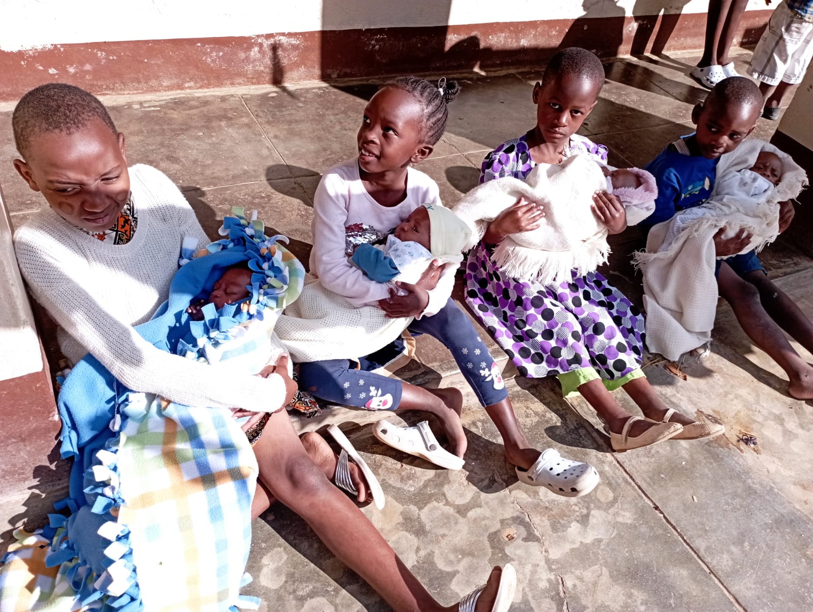 Small girls with their little sisters on their hands at St.Joseph Children's Home basking in the morning sun 